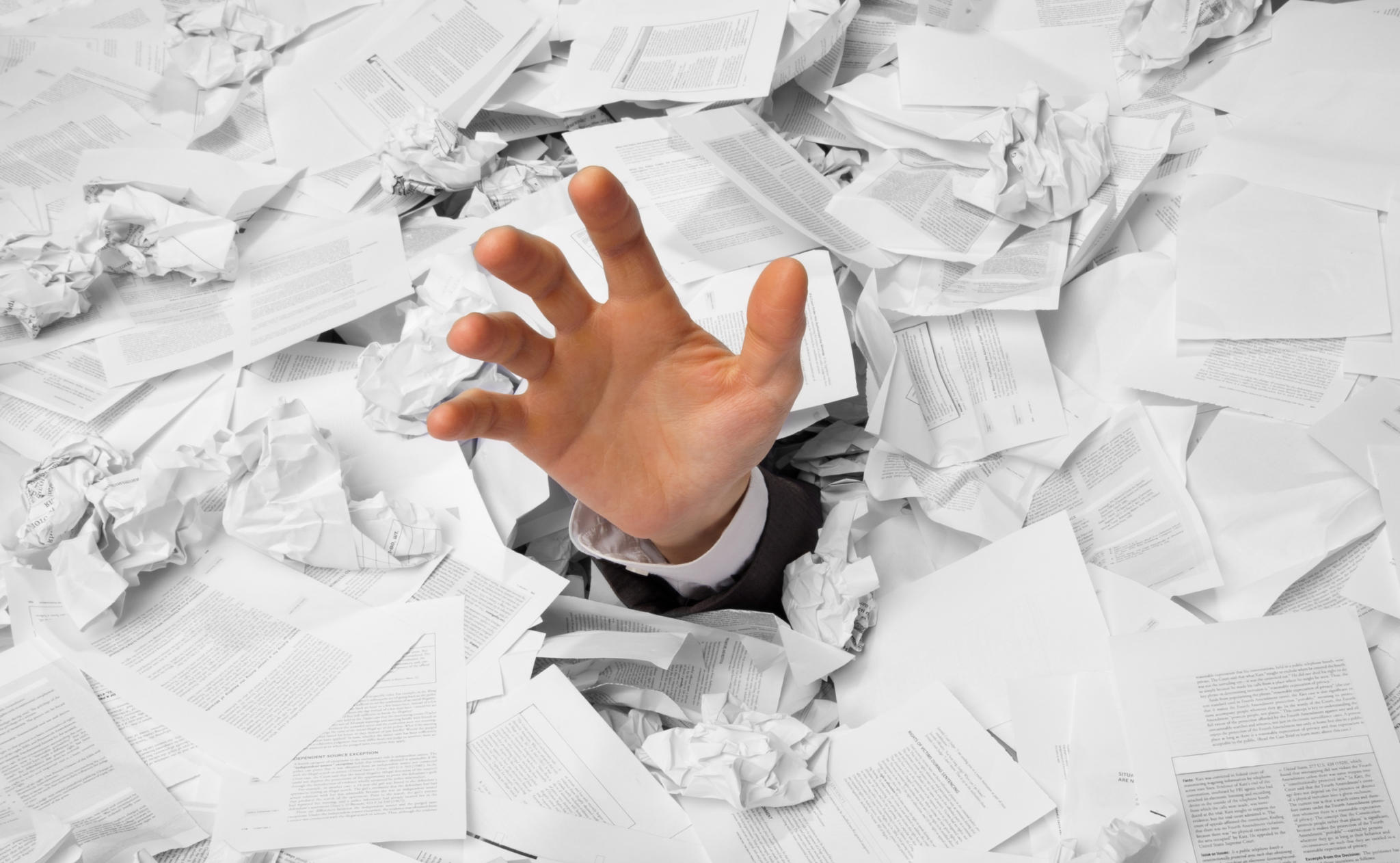 Recruiter's Hand Reaching Through A Pile of Resumes