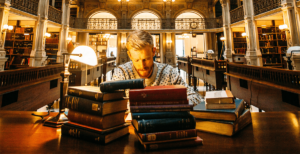 Man Working In Library Surrounded By Books