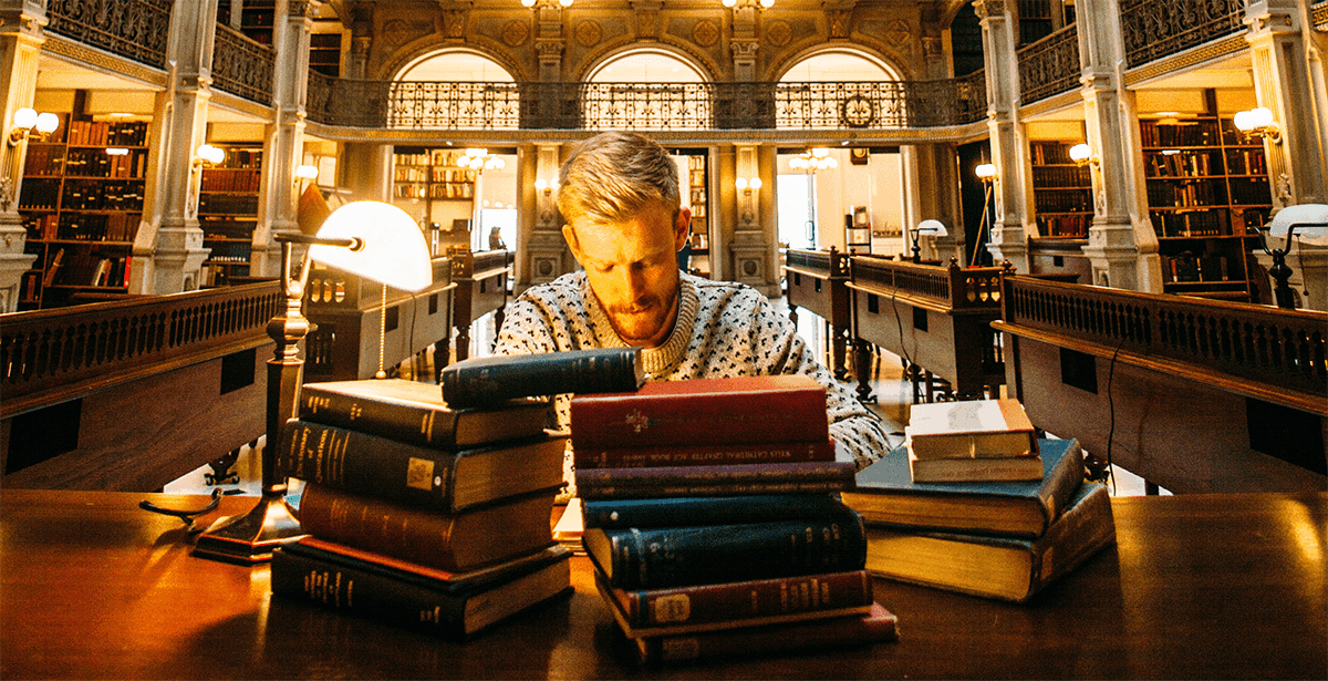 Man Working In Library Surrounded By Books