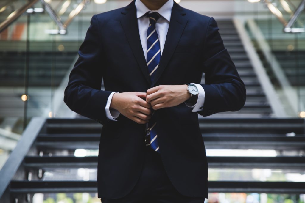 Man buttoning his suit jacket preparing to introduce himself